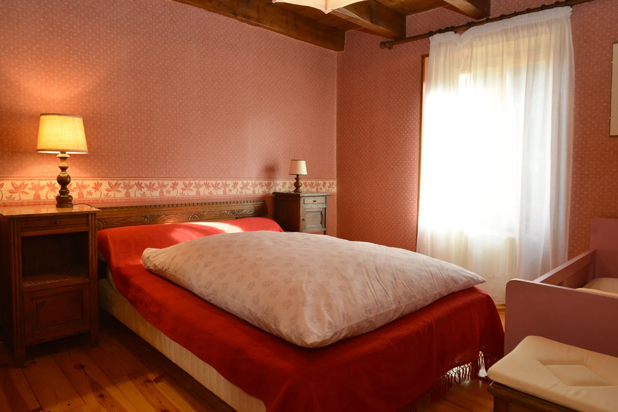 Chambre rouge pour deux personnes avec un lit double et quelques meubles